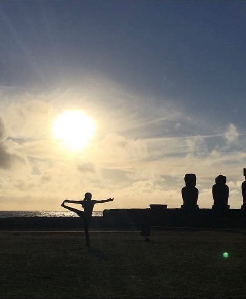 Alejandra haciendo yoga al atardecer frente a los moai de Rapa Nui